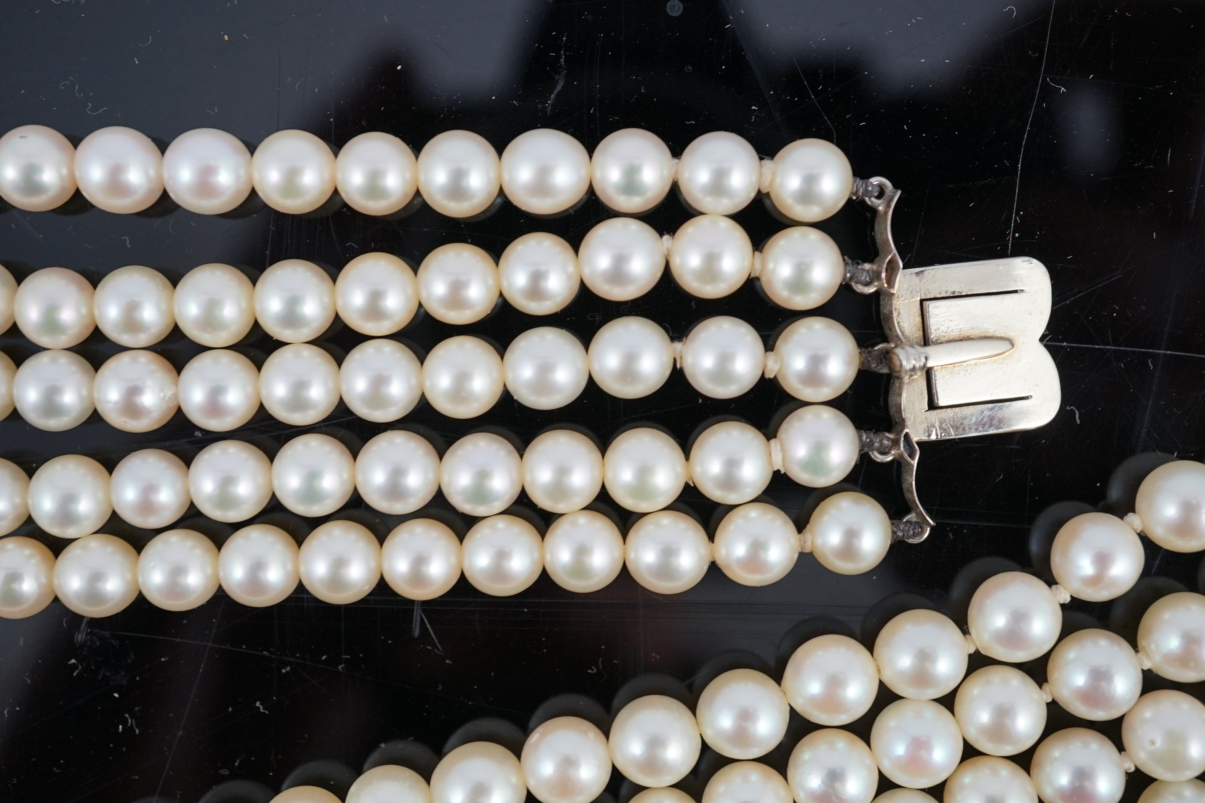 A mid 20th century quintuple strand cultured pearl choker necklace, with diamond cluster set white gold clasp and diamond cluster set white gold scrolling central motif, together with a matching bracelet